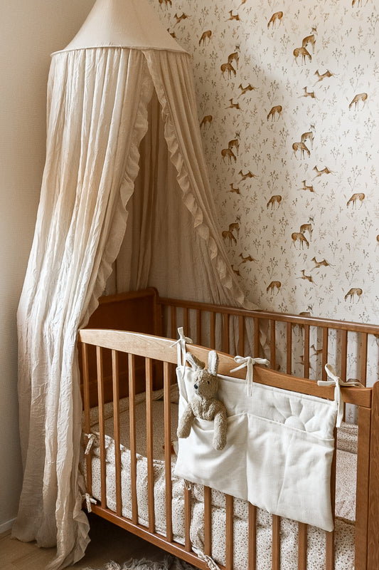 Matuu Deer Glade white wallpaper close-up with crib and delicate forest pattern