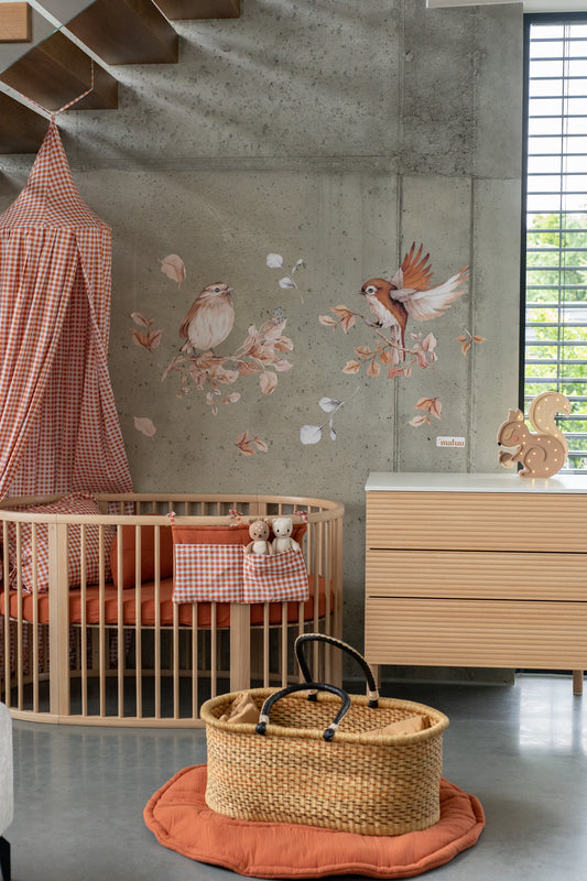 Bird and floral wall decals in a vintage-inspired nursery with a round wooden crib