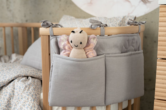 Spacious Matuu grey bed pocket tied to a wooden crib – ideal for storing toys and baby essentials