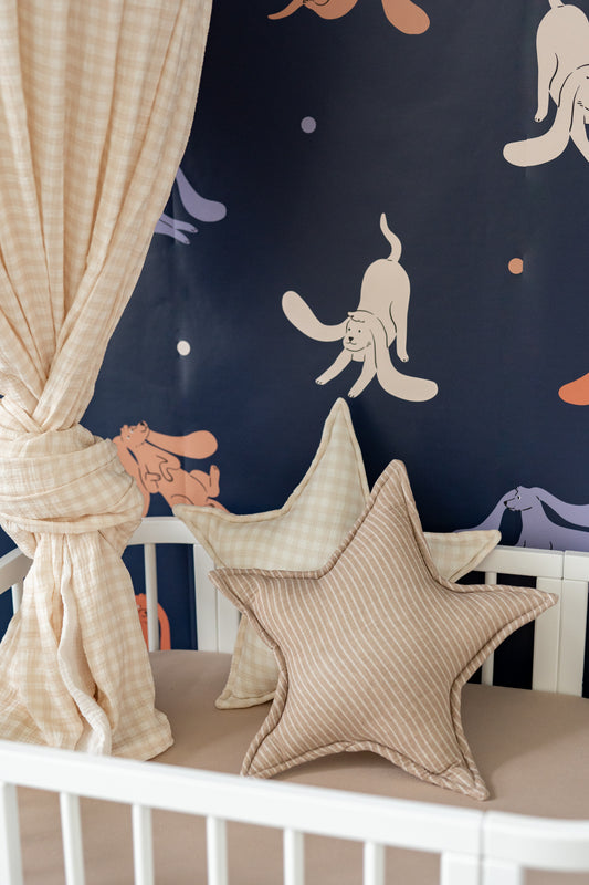 Close-up of Matuu dark blue wallpaper with floppy dog print – styled with canopy and star pillows for a cozy reading nook.