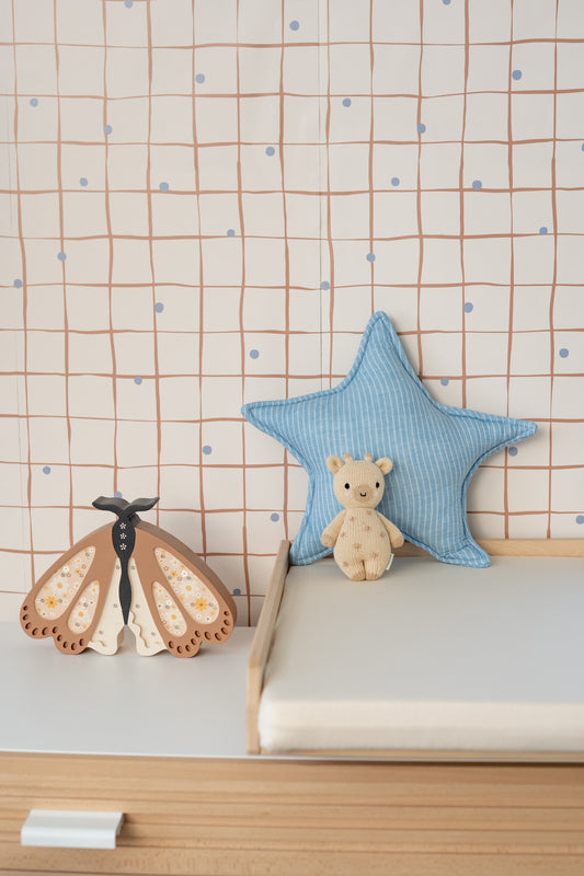 Rolls of Matuu wallpaper showing “Pebble Grid – Sand” and other colorways – textured grid with hand-drawn imperfections.