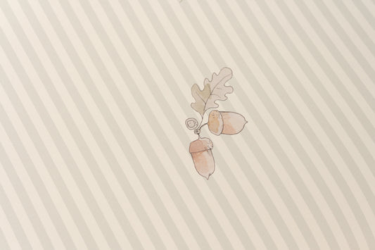 Close-up of Matuu Acorn Green wallpaper roll with wooden toy bear, botanical acorn design, Scandinavian nursery vibe