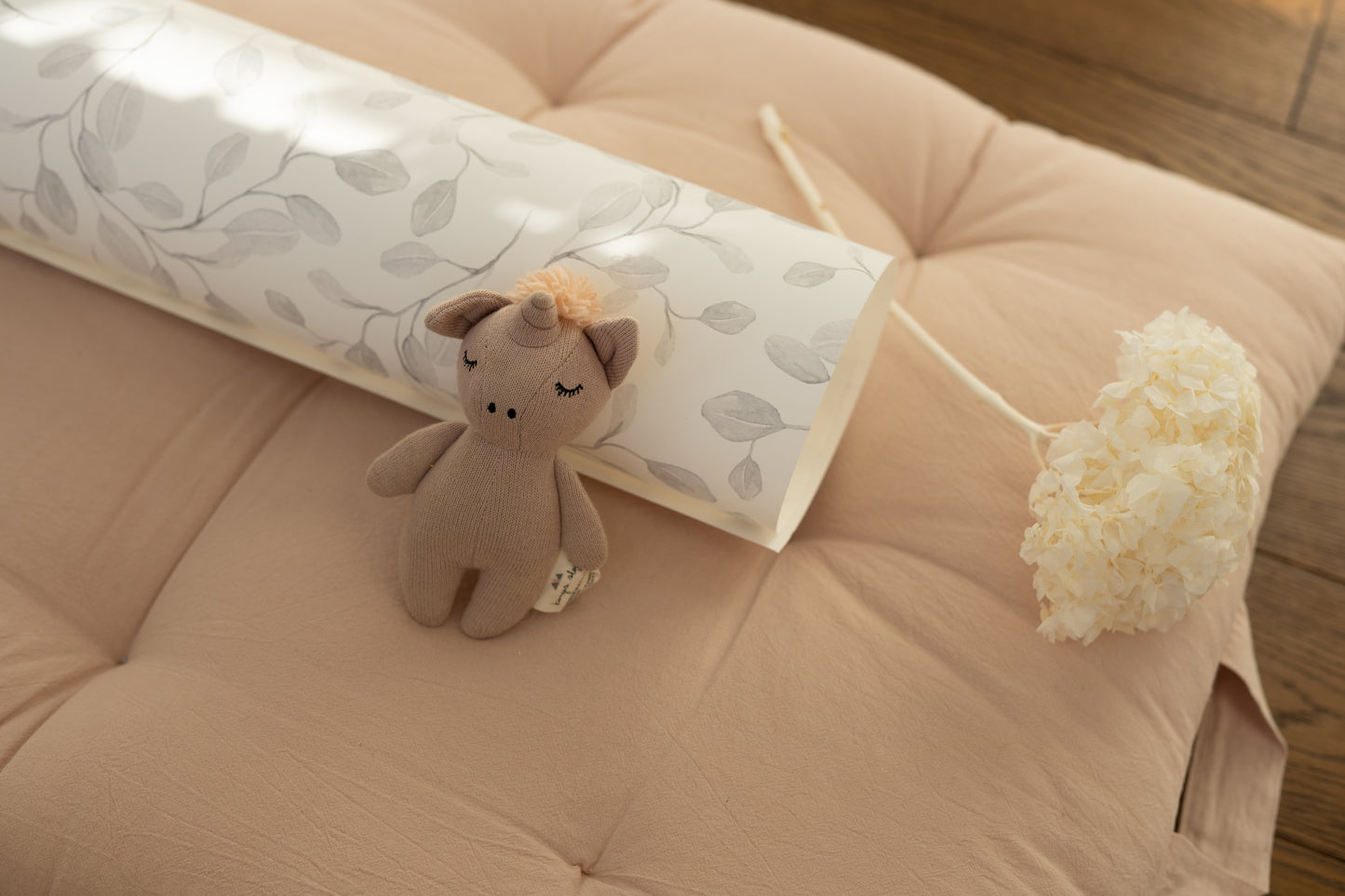 Rolled Eucalyptus Whimsy wallpaper with botanical pattern – styled with plush toy and dried flower on beige cushion