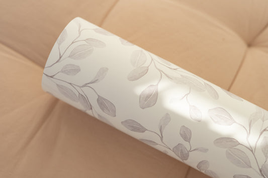 Close-up of Matuu Eucalyptus Whimsy grey botanical wallpaper roll on soft cushion