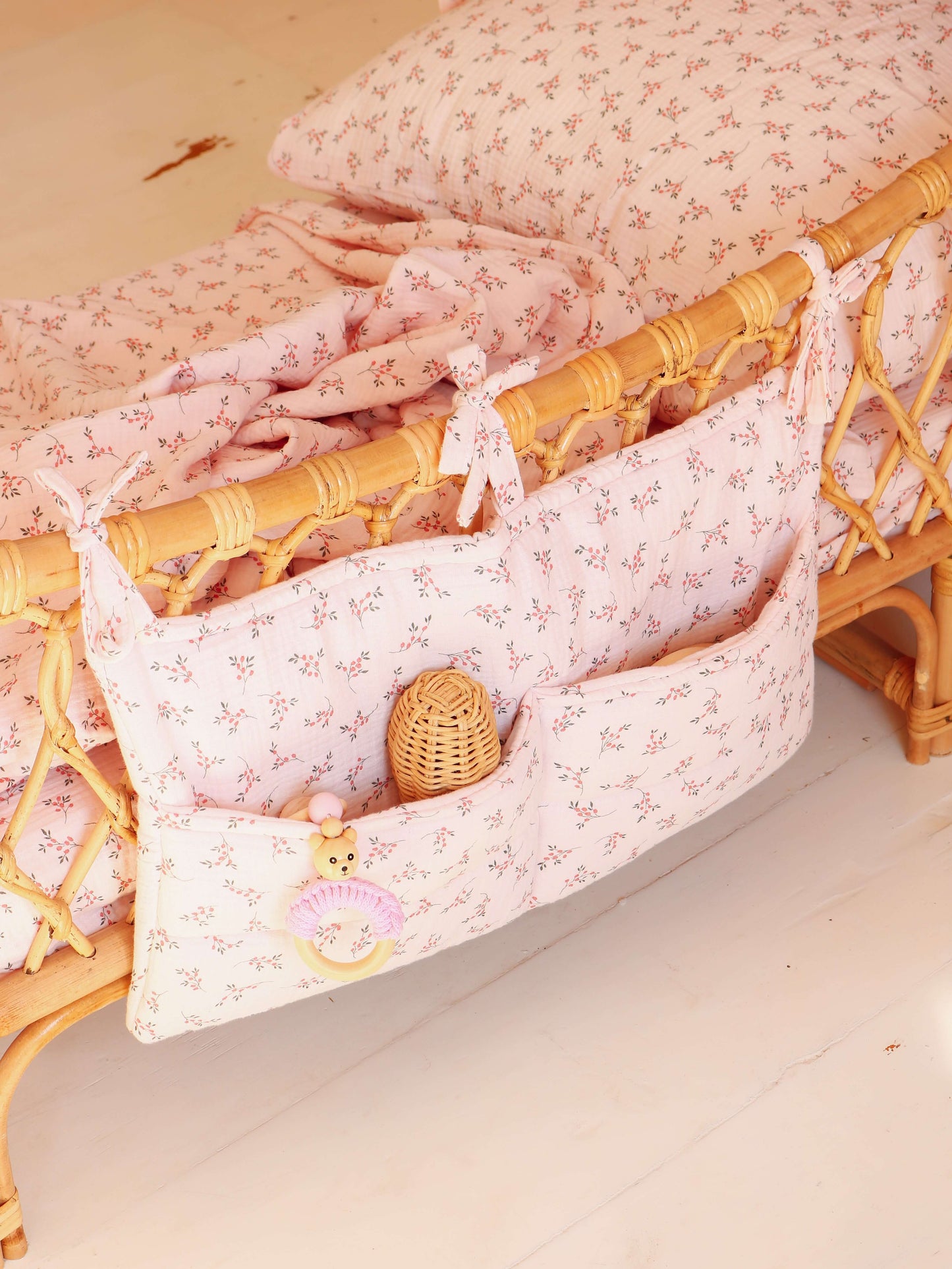Close-up of Matuu nursery organizer with bows and soft fabric – pastel pink with delicate flowers.