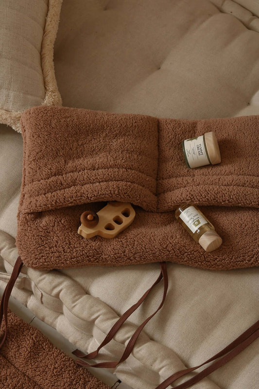 Close-up of Matuu teddy organizer – dark brown fleece with fabric ties and baby essentials inside