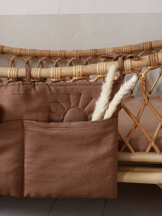 Close-up of Matuu brown linen bed pocket – quilted detail and neutral ties, filled with baby essentials.