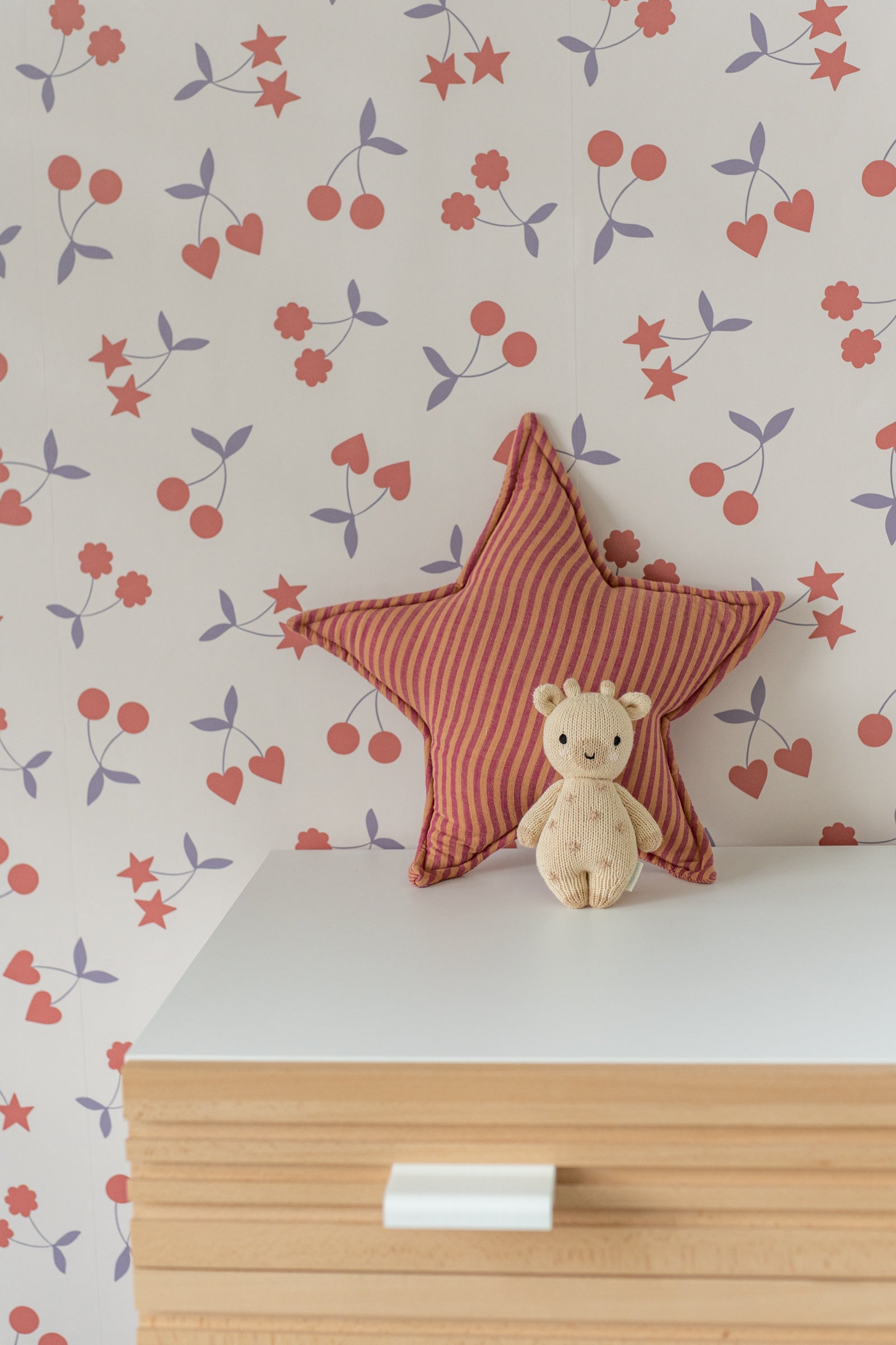 Close-up of a rust-colored star pillow on light wallpaper with heart motifs