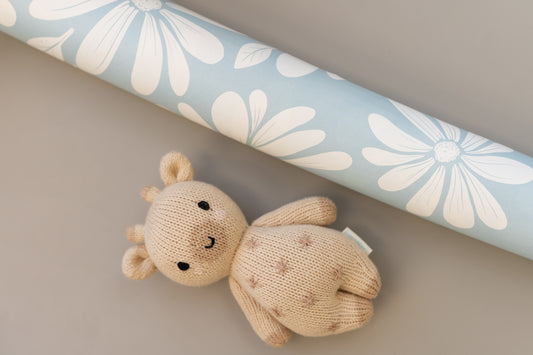 Matuu Aqua Blue wallpaper – rolled sample with white daisy pattern and a small teddy bear.