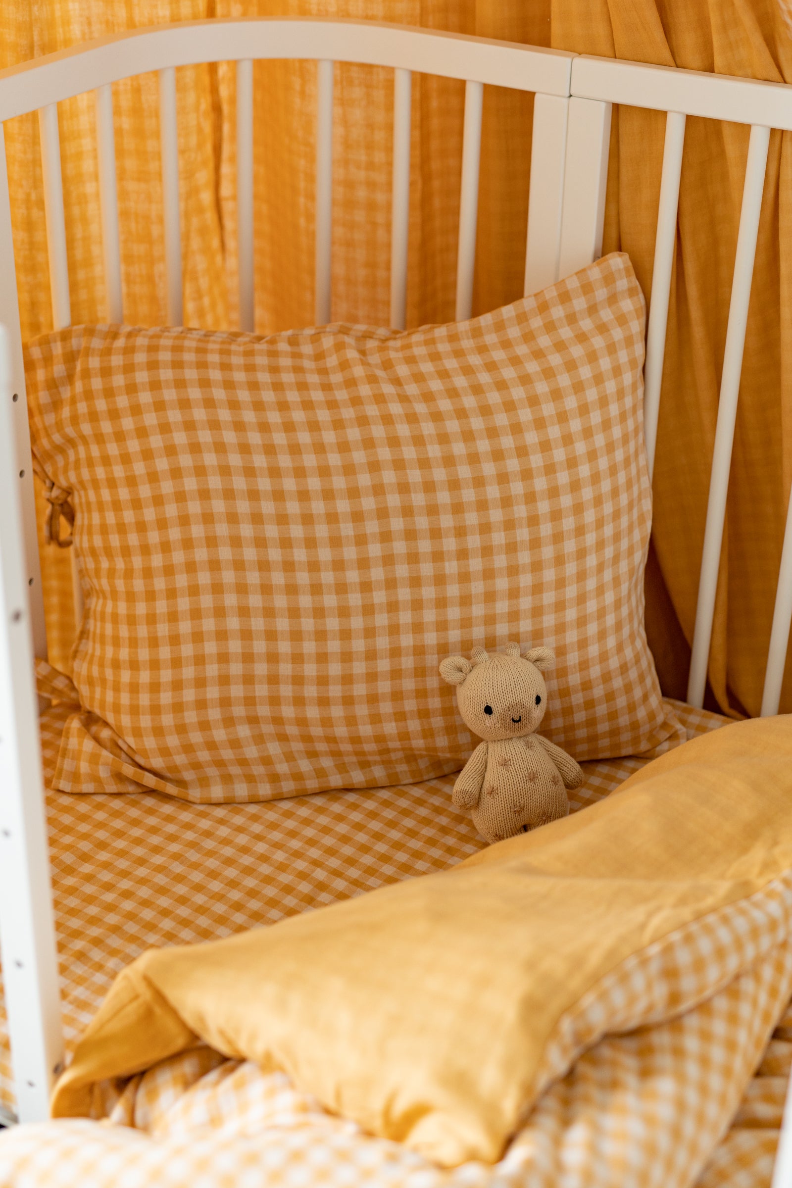 Yellow checkered bedding with a teddy bear on a bed